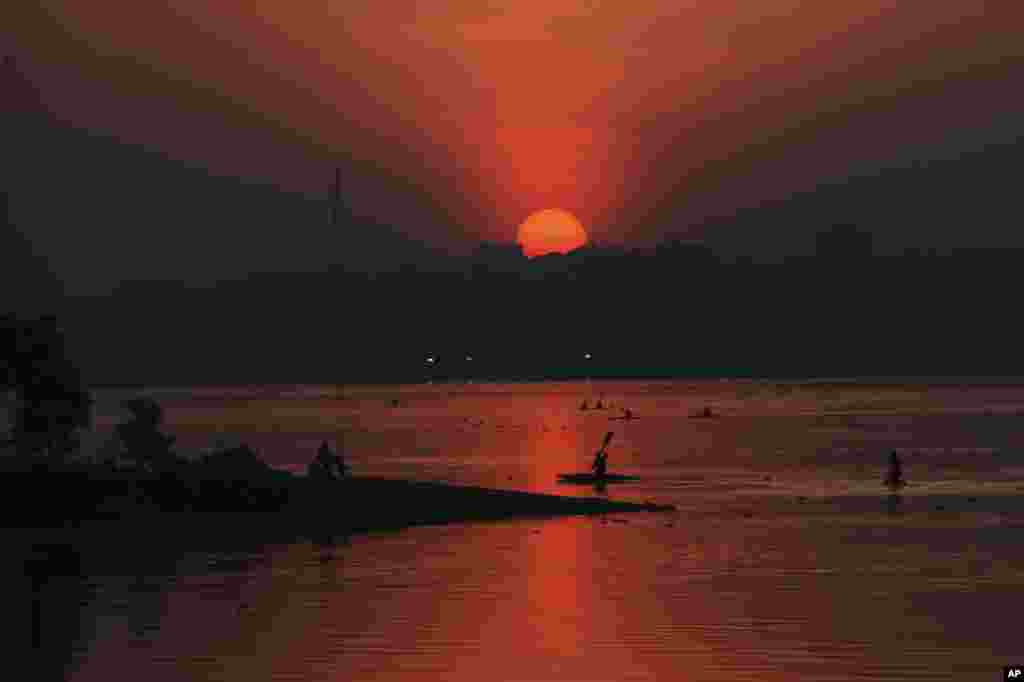 Indian sportsmen return to shore after canoeing practice as the sun sets at the Hussain Sagar Lake in Hyderabad, India. 