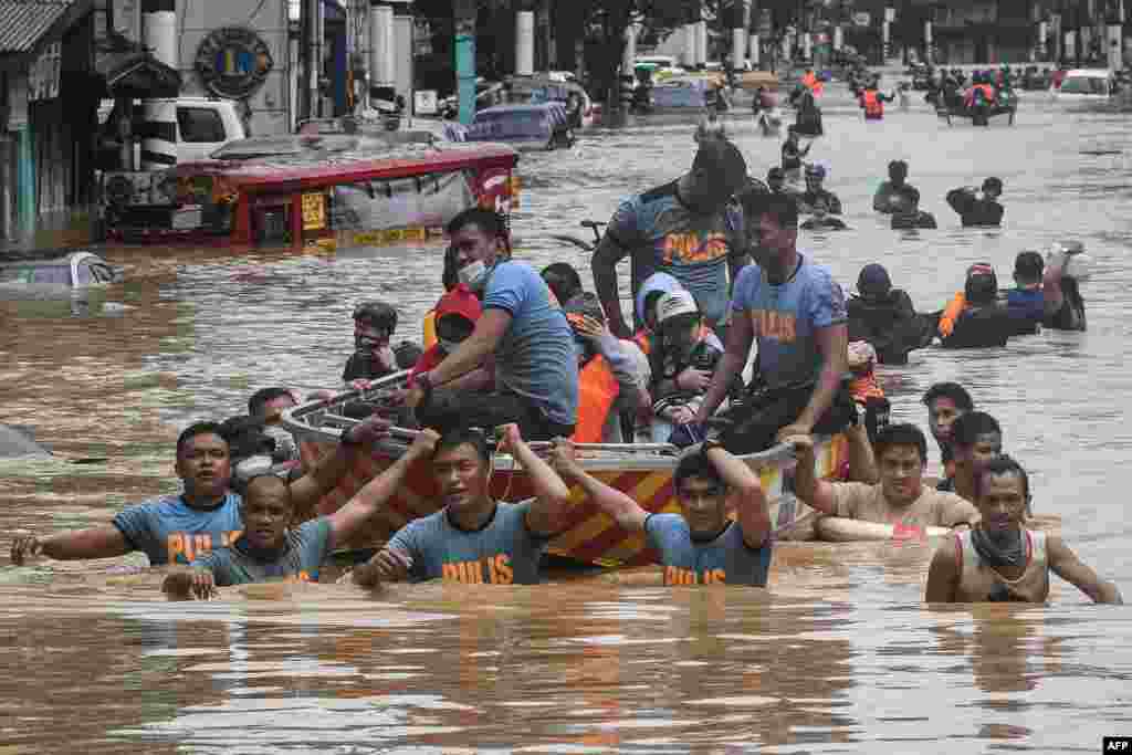 Rescuers pull a rubber boat carrying residents through a flooded street after Typhoon Vamco hit in Marikina City, suburban Manila, Philippines.