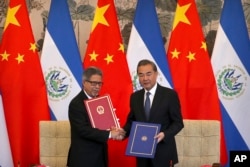 FILE - El Salvador's Foreign Minister Carlos Castaneda, left, and China's Foreign Minister Wang Yi shake hands at a signing ceremony to mark the establishment of diplomatic relations between the two countries at the Diaoyutai State Guesthouse in Beijing, Aug. 21, 2018.