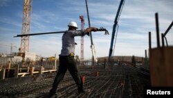 FILE - A laborer works on an apartment building project in a Jewish settlement known to Israelis as Har Homa and to Palestinians as Jabal Abu Ghneim in the West Bank.