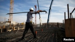 FILE - A laborer works on an apartment building project in a Jewish settlement known to Israelis as Har Homa and to Palestinians as Jabal Abu Ghneim in an area of the West Bank that Israel captured in the 1967 war and annexed to Jerusalem, Oct. 28, 2014.