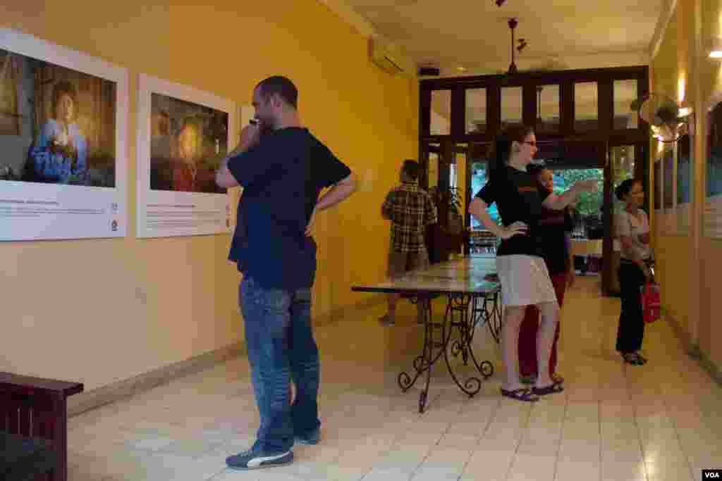 People look at photos of abuse victims at the &quot;No one should work this way&quot; exhibit at the Foreign Correspondents Club of Phnom Penh, May 7, 2015. (Photo: Nov Povleakhena/VOA Khmer)