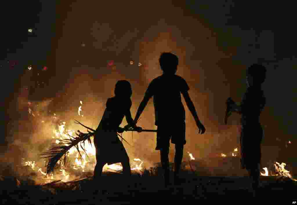 Filipino boys try to put out the fire from burning garbage near their makeshift homes in Manila.