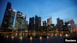 FILE - FILE - People walk past the skyline of Marina Bay central business district in Singapore.