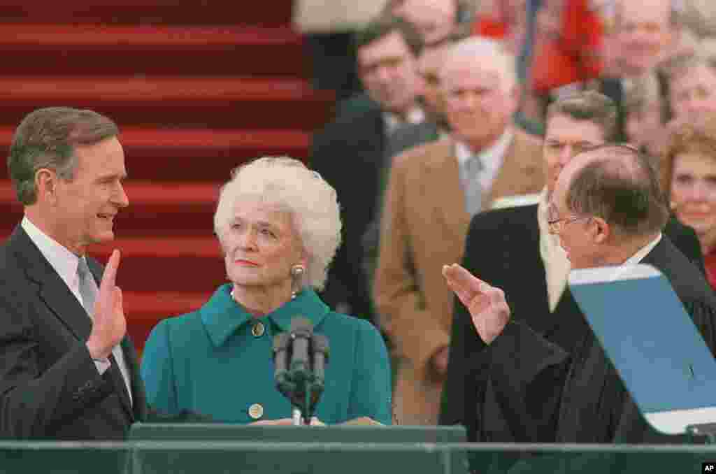 George H. W. Bush raises his right hand as he is sworn into office as the 41st president of the United States by Chief Justice William Rehnquist outside the west front of the Capitol on January 20, 1989. 