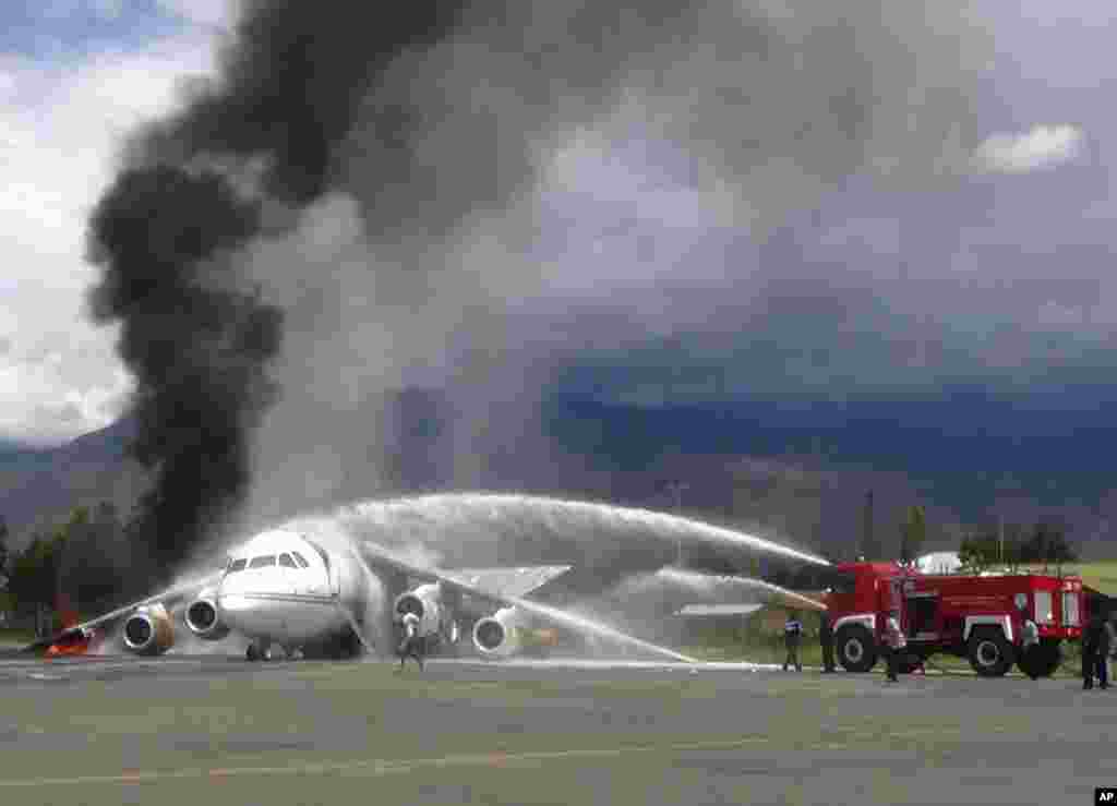 Fire fighters try to extinguish fire on a British-made BAe 146 cargo plane that caught fire while being unloaded at the airport in Wamena, Papua province, Indonesia. An official said that the plane caught fire after a drum of oil fell from the aircraft and somehow sparked the fire.