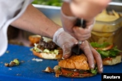 FILE - French burgers are prepared at 'Le Refectoire' food truck in Paris, Nov. 16, 2012.