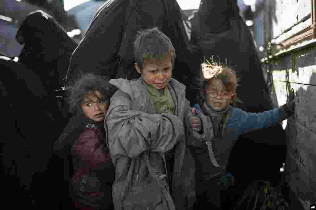 Women and children exit the back of a truck as they arrive to a U.S.-backed Syrian Democratic Forces (SDF) screening area after being evacuated out of the last territory held by Islamic State militants, in the desert outside Baghouz, Syria.