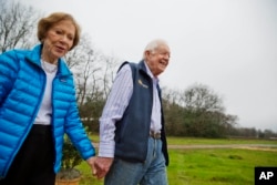 FILE - In this Feb. 8, 2017, file photo former President Jimmy Carter, right, and his wife Rosalynn arrive for a ribbon cutting ceremony for a solar panel project on farmland he owns in their hometown of Plains, Georgia. (AP Photo/David Goldman, File)