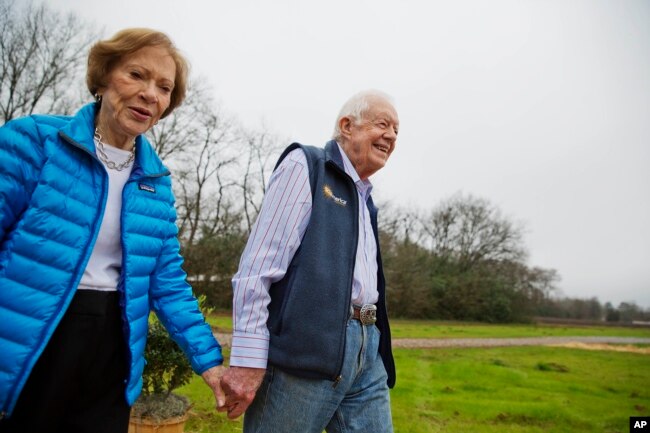 FILE - In this Feb. 8, 2017, file photo former President Jimmy Carter, right, and his wife Rosalynn arrive for a ribbon cutting ceremony for a solar panel project on farmland he owns in their hometown of Plains, Georgia. (AP Photo/David Goldman, File)