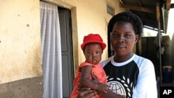 Jackie Aciro and her daughter outside the rooms she rents in Gulu, where she lives because she is unable to farm her husband's land, April 19, 2012. 
