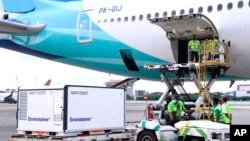 Pekerja menurunkan peti kemas berisi vaksin percobaan virus corona buatan perusahaan China Sinovac dari ruang kargo pesawat Garuda Indonesia di Bandara Soekarno-Hatta. (Foto: via AP)