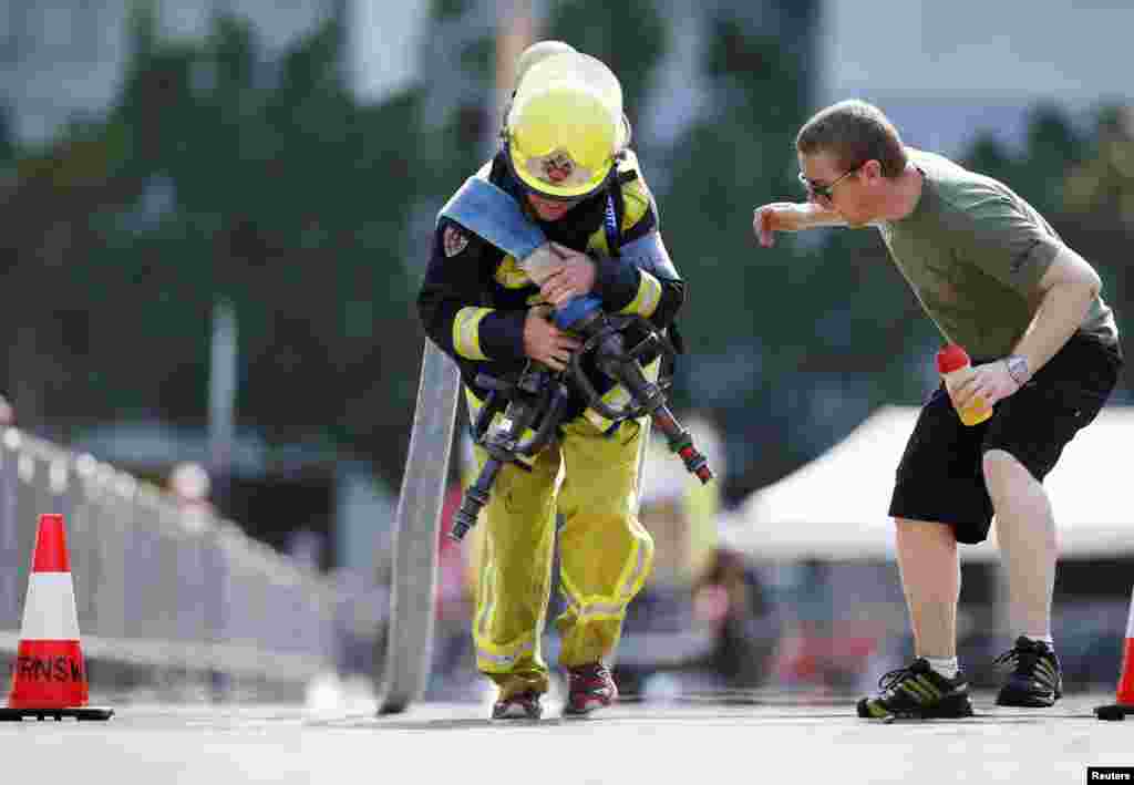 A teammate cheers a firefighter from South Africa as he competes in the Toughest Firefighter event at the 12th World Firefighter&#39;s Games in Sydney, Australia. 