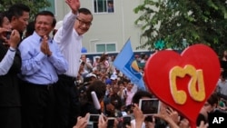 Opposition Cambodia National Rescue Party (CNRP) leader Sam Rainsy, right, accompanied by his party's Vice President Kem Sokha, second from right, waves to his party supporters during a public forum of the July 28 election result, in Phnom Penh, file photo. 