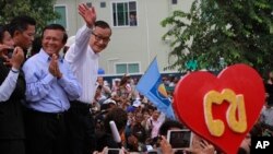 Opposition Cambodia National Rescue Party (CNRP) leader Sam Rainsy, right, accompanied by his party's Vice President Kem Sokha, second from right, waves to his party supporters during a public forum of the July 28 election result, in Phnom Penh, file photo. 