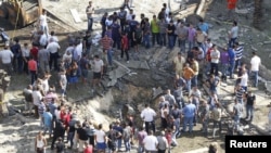 Residents gather around a crater caused by one of the two explosions outside one of two mosques in Lebanon's northern city of Tripoli, August 23, 2013. 