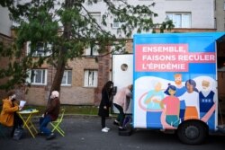 Seorang perempuan memasuki truk vaksinasi untuk menerima dosis vaksin COVID-19 di luar gedung tempat tinggalnya di kota Stains, pinggiran kota Paris, Perancis, 2 Maret 2021. (Foto: Anne-Christine POUJOULAT / AFP)