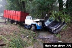 Un camion et une voiture se trouvent dans un ruisseau, dimanche 22 août 2021, après avoir été emportés par les eaux la veille à McEwen, Tennessee.