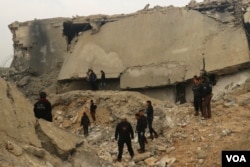 Civil defense members and other people inspect a damaged mosque after an airstrike on the village of al-Jinah, Aleppo province, in northwest Syria, March 17, 2017.