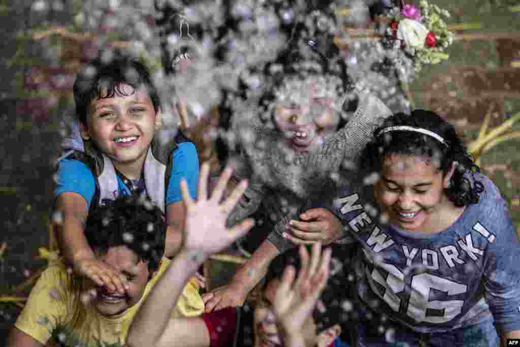 Egyptian Coptic Orthodox Christian children react after being sprayed with holy water by a priest at the Saint Simon Church, also known as the Cave Church, in the Mokattam district in the capital Cairo during a mass marking Palm Sunday.