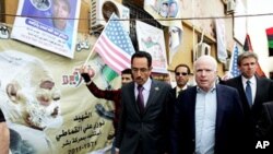 US Republican senator John McCain (R) walks with Abdul Hafiz Ghoqa, spokesman of the Libyan National Transitional Council (NTC), during his tour to the rebel headquarters in their eastern stronghold city of Benghazi , April 22, 2011