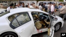 Des enquêteurs et journalistes pakistanais entourent la voiture portant des traces sang du célèbre chanteur soufi Amjad Sabri après l'attaque dont il a été victime à Karachi, au Pakistan, le mercredi 22 juin 2016.