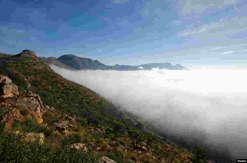 Vehicles drive along the scenic Ou Kaapse Weg as seasonal fog covers the city in Cape Town, South Africa.