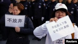 Para anggota keluarga penumpang pesawat MH370 yang hilang 8 Maret tahun 2014, membawa tulisan dalam unjuk rasa di Beijing