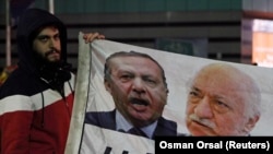 FILE - A demonstrator hold pictures of Turkey's Prime Minister Tayyip Erdogan and Turkish cleric Fethullah Gulen (R), during a protest in Istanbul Dec. 30, 2013. 