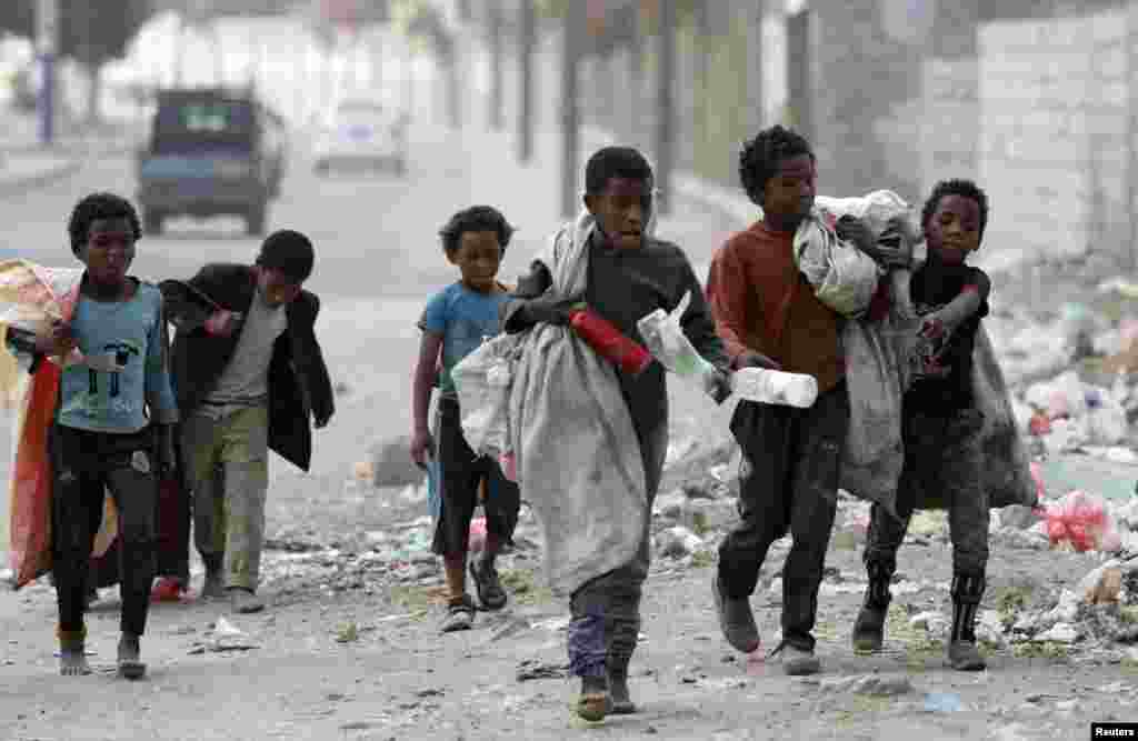 Children walk as they collect empty plastic bottles in a street in Sana&#39;a, Yemen.