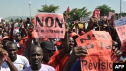 FILE - In a protest over a previous constitutional change, protestors carry a sign reading "No to the referendum" and "No to Constitutional revision" during a demonstration against a referendum on July 1, 2017, in Bamako. 