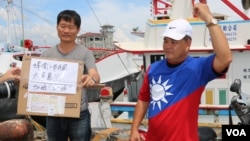 台湾屏东渔民发起的“保祖产 护主权”活动发言人罗强飞与一名参与者展示台中网友寄来的以青天白日旗为图案的T恤。