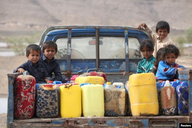 FILE - Children ride on the back of a truck loaded with water jerrycans at a camp for internally displaced people in the Dhanah area of the central province of Marib, Yemen, April 30, 2016.