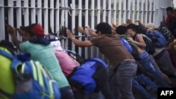 Honduran migrants taking part in a caravan heading to the US, tear down the border fence between Ciudad Tecun Uman in Guatemala and Ciudad Hidalgo, Mexico, Oct. 28, 2018.