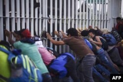 FILE - Honduran migrants taking part in a caravan heading to the U.S. tear down the border fence between Ciudad Tecun Uman in Guatemala and Ciudad Hidalgo, Mexico, Oct. 28, 2018.