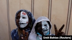 Sudanese girls with painted faces make victory signs as they watch protesters in Khartoum, Sudan