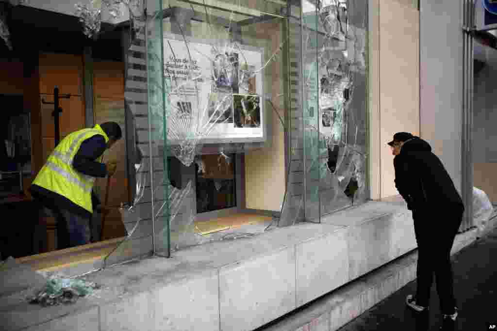 A worker clears debris in a bank in Paris, France. Paris monuments reopened, public workers cleared debris and shop owners tried to put the city on its feet again after running battles between yellow-vested protesters and riot police left 71 injured and caused widespread damage to the French capital.