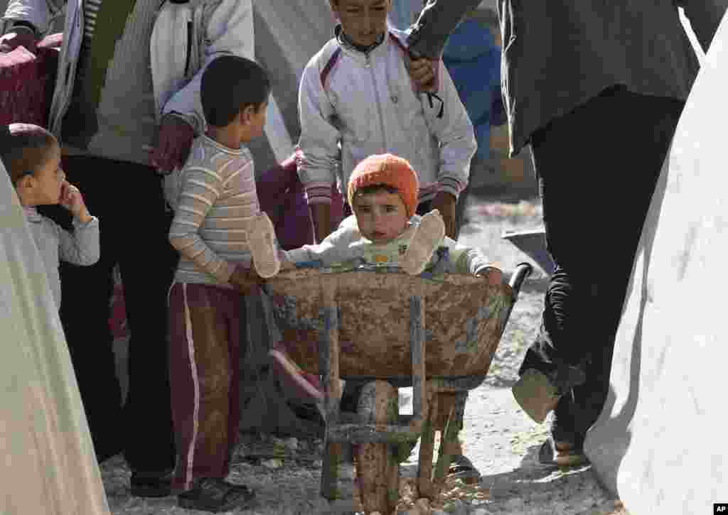 A Syrian Kurdish refugee child from the Kobani area is transported in a wheelbarrow at a camp in Suruc, Nov. 12, 2014.