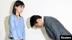 Tokyo city assembly lawmaker Akihiro Suzuki (R) bows to apologize to female lawmaker Ayaka Shiomura at Tokyo Metropolitan City Hall, in this photo taken by Kyodo, June 23, 2014. 