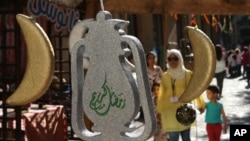 A Lebanese woman with her children walk past traditional lanterns and crescents displayed for sale for the upcoming holy month of Ramadan, in downtown Beirut, Lebanon, June 14, 2015.