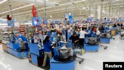 FILE - Cashiers work checkout lanes of a Walmart store in the Porter Ranch section of Los Angeles, California.