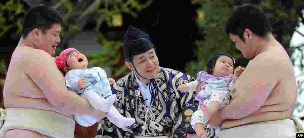 Student sumo wrestlers carry crying babies beside a referee (C) clad in a traditional costume during the &quot;Baby-cry Sumo&quot; competition at Sensoji temple in Tokyo, Japan. 