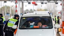 Polisi China menggunakan termometer memeriksa suhu tubuh seoran pengendara di kota Wuhan (23/1).