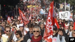 Demonstrators march during a rally with banners and flags to protest against the austerity measures announced by the French government, in Paris, Sunday, Sept 30, 2012.
