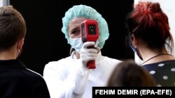 A medical staff measures a body temperature to people arriving to tests for coronavirus, at a hospital in Sarajevo, Bosnia and Herzegovina, 21 September 2020. 