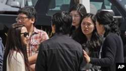 Students and onlookers at Oikos University talk amongst themselves at the scene of a multiple shooting at the school in Oakland, California, April 2, 2012.