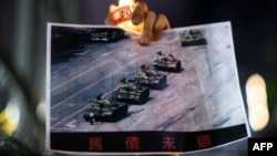 资料照：在香港维多利亚公园参加纪念六四事件31周年的一名男子手持天安门广场“坦克人”的照片。（2020年6月4日）
