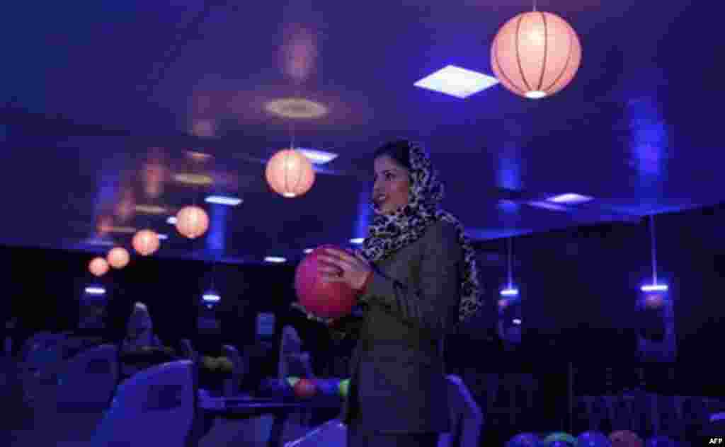 In this Friday, Oct. 28, 2011 photo, Meena Rahmani, 26, owner of The Strikers, the country's first bowling center, holds a bowling ball in Kabul, Afghanistan. In an Afghan capital scarred by years of war, a young Afghan woman has bet $1 million that the c