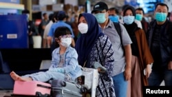 Para penumpang antri untuk menjalani pemeriksaan suhu tubuh di bandara Halim Perdanakusuma, Jakarta di tengah perebakan virus corona (20/3). 