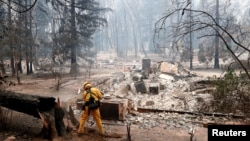 A firefighter extinguishes a hot spot in a neighborhood destroyed by the Camp Fire in Paradise, California, Nov. 13, 2018. 